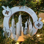 Laser cut ornament positioned in a tree - the ornament is made of 3 layers depicting a NYC skyline 