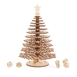 A single laser-cut wooden Christmas tree with tiered snowflake branches, featuring a white star finial topper and miniature colorful gift box and a cat and dog accents at the base.