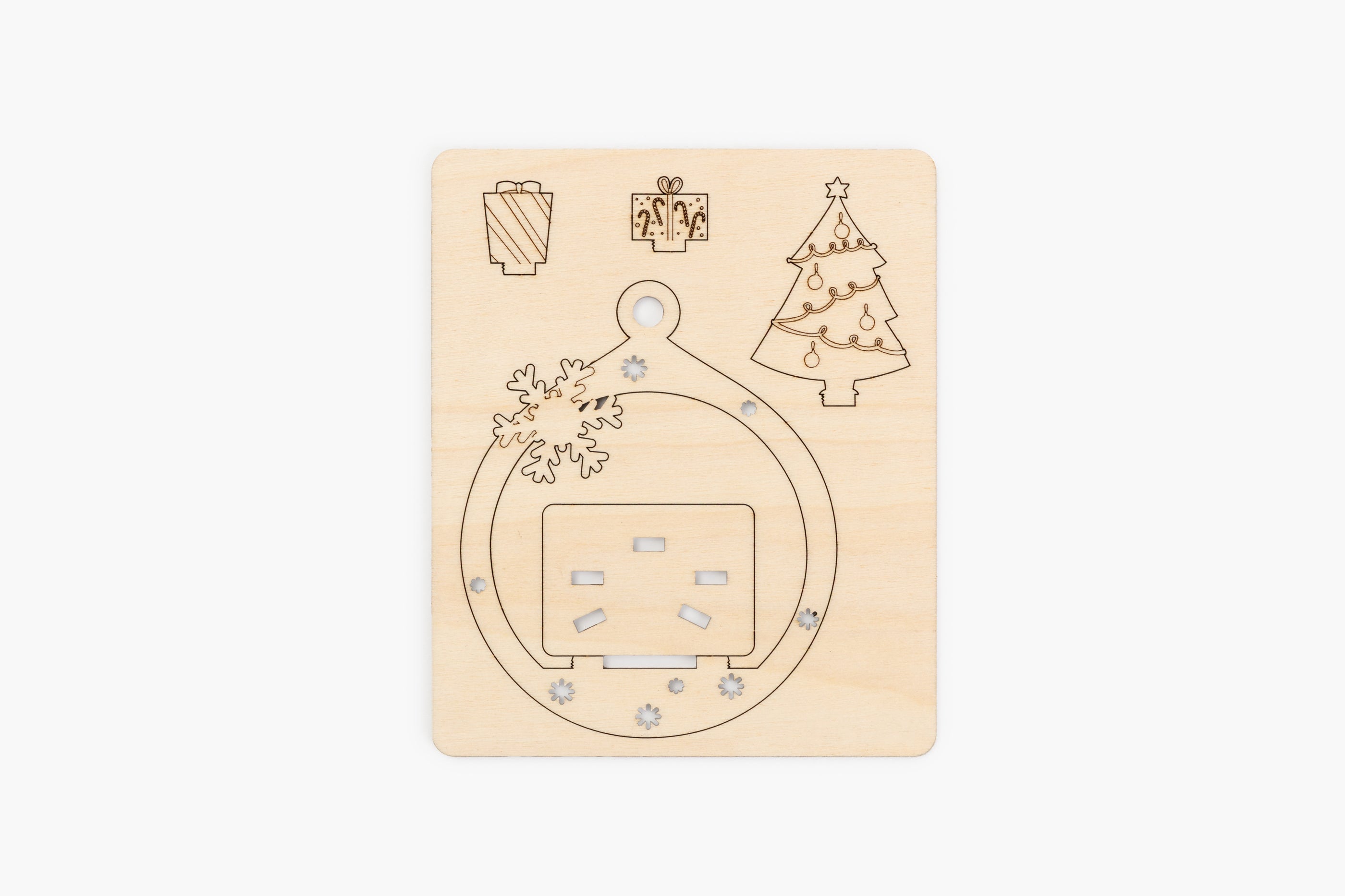 Wooden plate showing laser cut  with Christmas-themed cutouts on a beige background