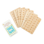 A set of six precision laser-cut binary magic cards laid out with a printed instruction sheet featuring a scannable barcode that reveals the secret mathematical solution